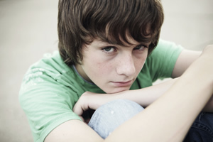 A sad looking teenage boy in a green shirt